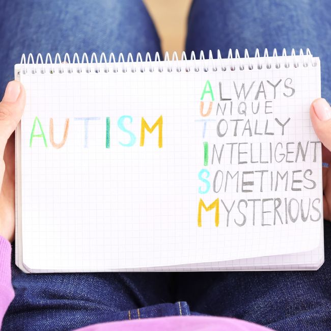 a person holding up a notebook with the word autism on it